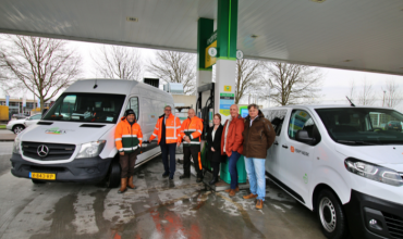 Een groep mensen van Punt, Ferm Werk en de gemeente staat voor auto's van Punt en Ferm Werk.
