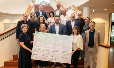 Een groep mensen houdt het ondertekende Samenwerkingsconvenant Arbeidsmarktregio Midden-Holland omhoog.