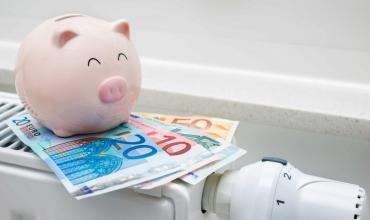 Radiator met daarop een stapeltje geld en daarop een roze spaarvarken