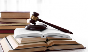 Een voorzittershamer ligt op een stapel wetsboeken.