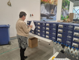 Een Ferm Werk medewerker ziet toe op de verpakking van de dozen met veiligheidsschoenen.